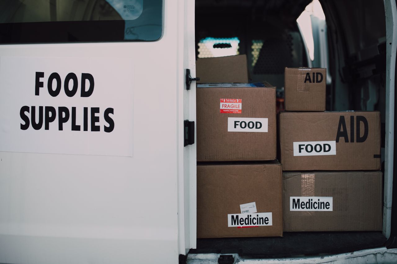 about-us Stacked donation boxes labeled food and medicine in a delivery van for charity aid.